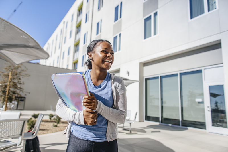 A UC Merced student holds her laptop after studying outside